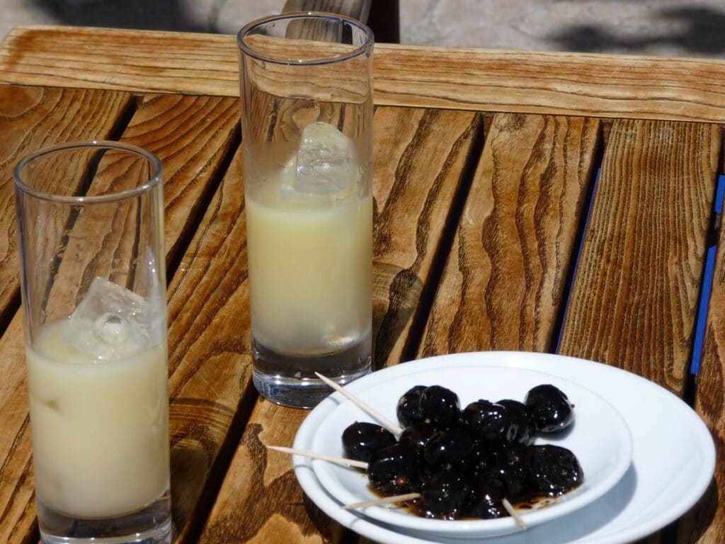 Deux verres de pastis sur une table avec des olives noires